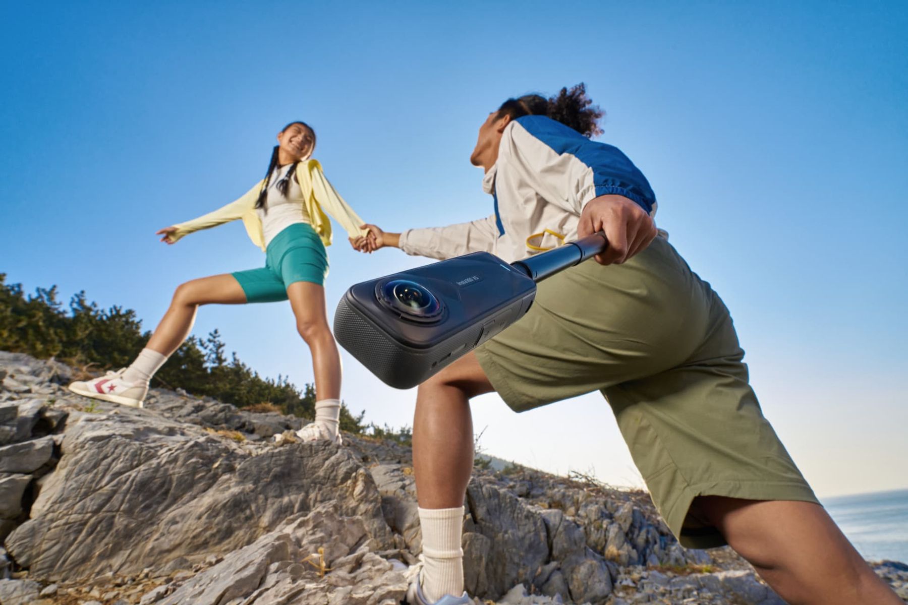 Couple hiking a rocky ridge filming with the Insta360 X5 on a stick