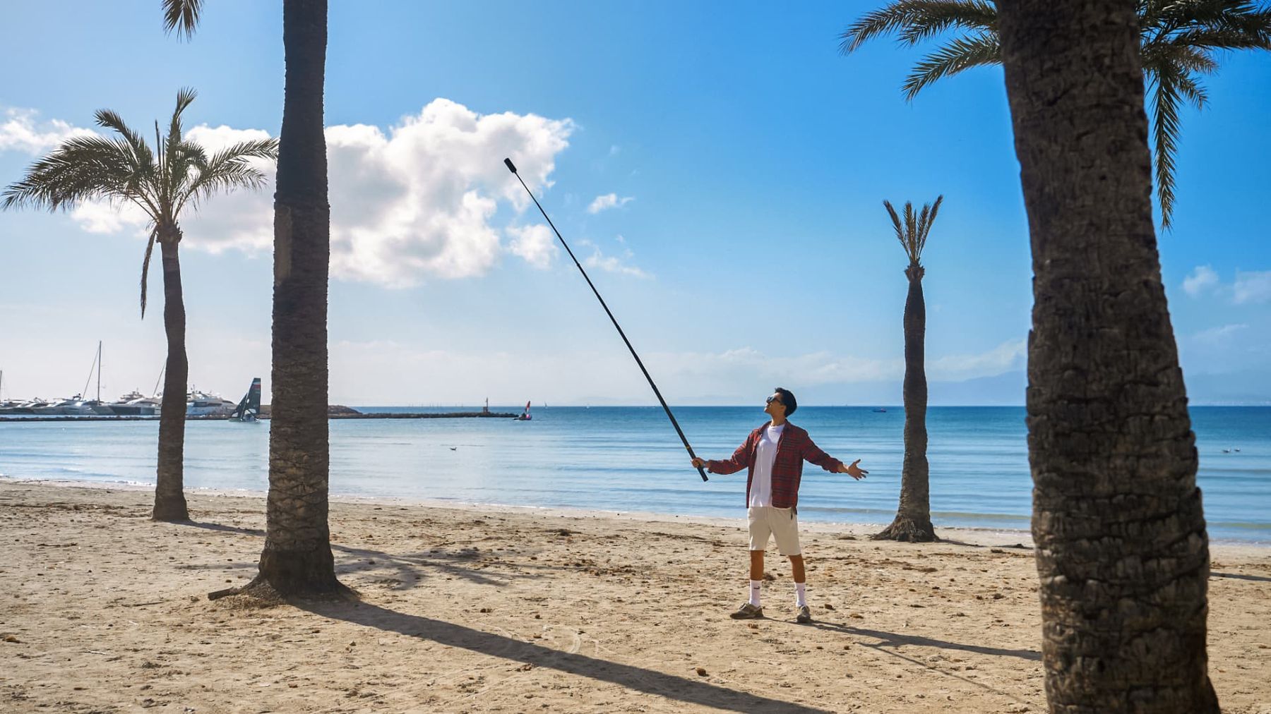Man on a palm beach filming with the X5 on an extended selfie stick