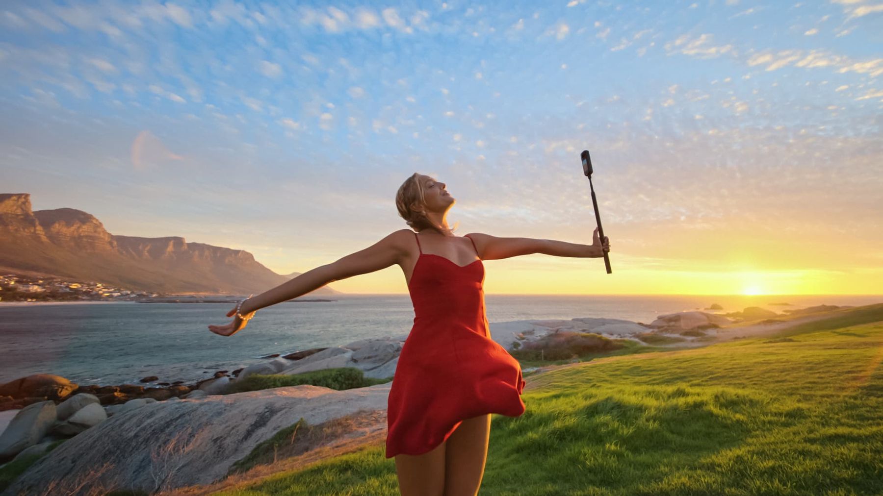 Woman filming at sunset by the coast in low light